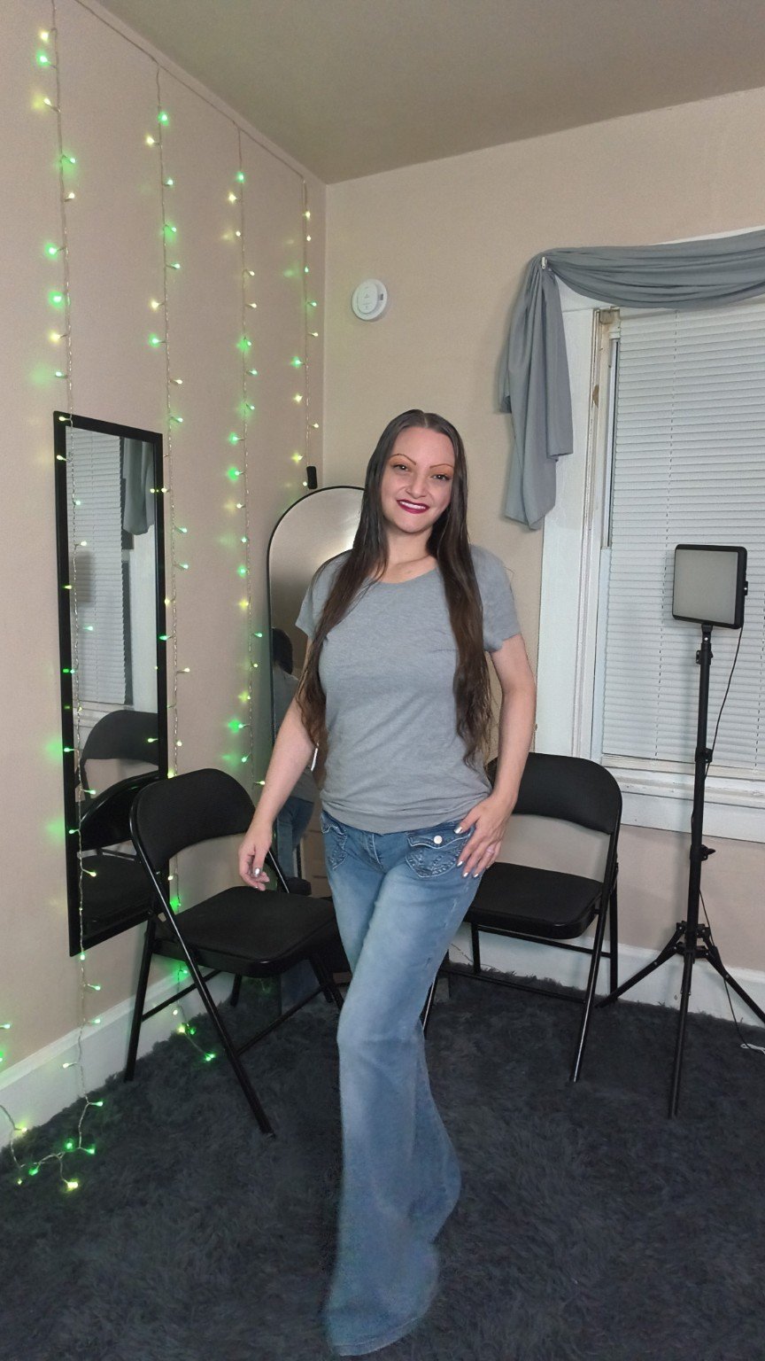 Ren wearing blue flare jeans beside her studio light stand
